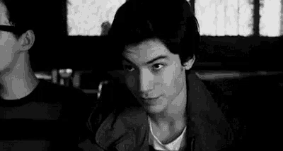 a black and white photo of a young man sitting in a restaurant .