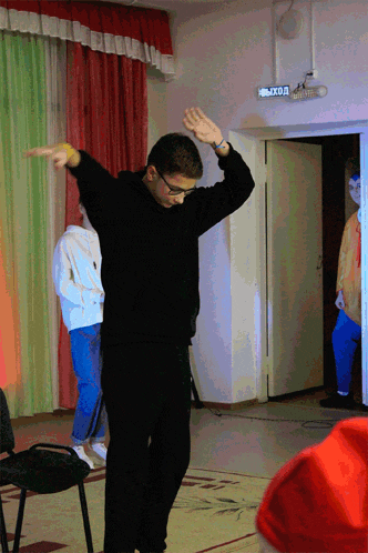 a man in a black sweater is dancing in front of a sign that says выход