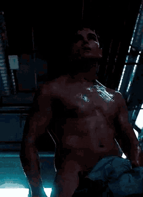a shirtless man is standing in a dark room holding a towel .