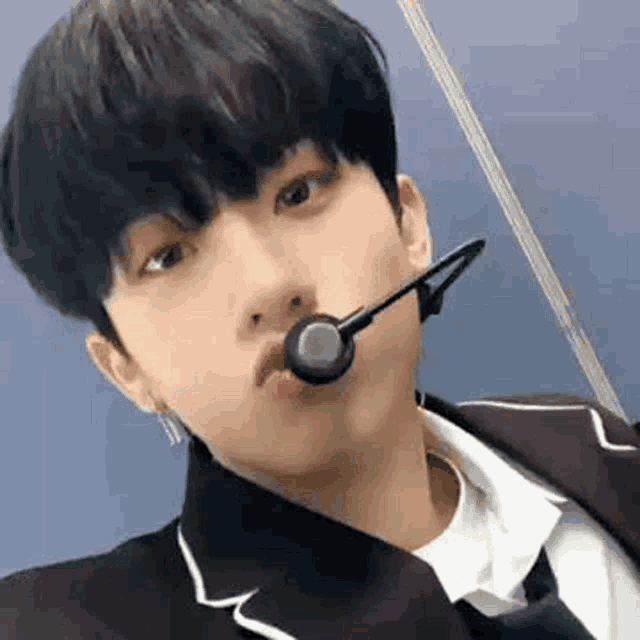 a young man is wearing a microphone in his mouth and taking a selfie .