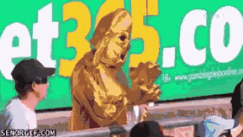 a man in a gold costume stands in front of a green sign that says et365.co