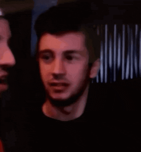 two men are standing next to each other in a dark room .