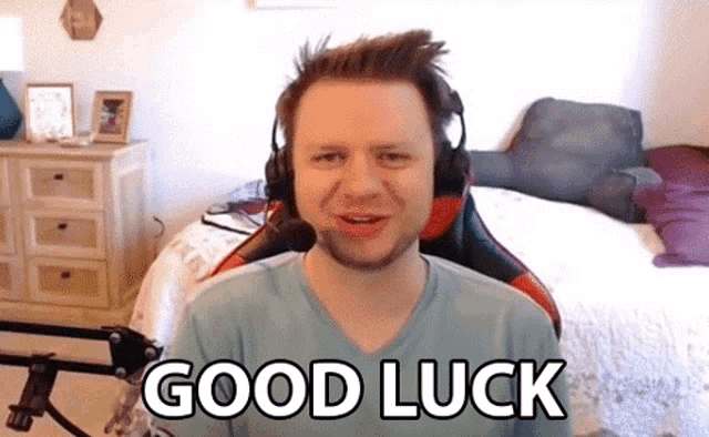 a man wearing headphones is sitting in front of a bed and says good luck .