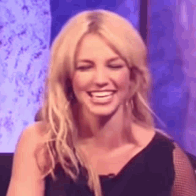 a close up of a woman laughing with her eyes closed and a purple background .