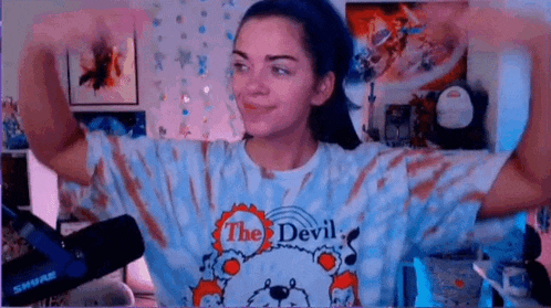 a woman is flexing her muscles while wearing a tie dye shirt .