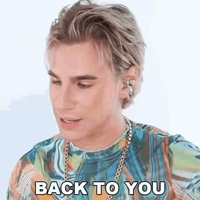 a man wearing a colorful shirt and a chain says back to you