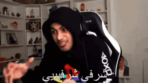 a man in a black hoodie is sitting in a white chair .