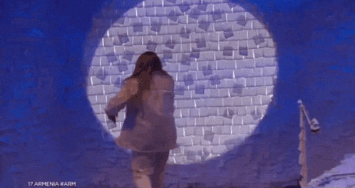 a woman is standing in front of a wall that says 17 armenia on it