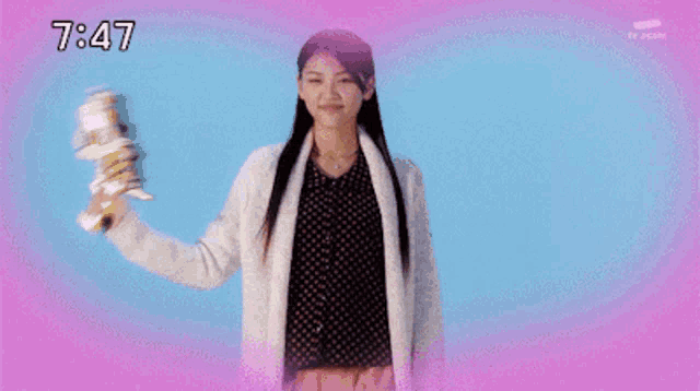 a woman is smiling in front of a pink background and the time is 7:47 .