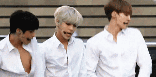 three men in white shirts are standing next to each other on stage .