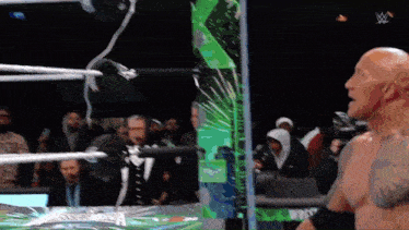 a man in a wrestling ring with a green sign that says ' wwe ' on it