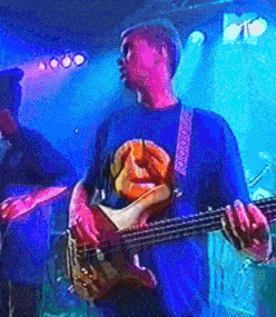 a man in a blue shirt with a face on it is playing a guitar