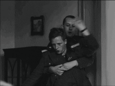 a man in a military uniform is holding another man in his arms .