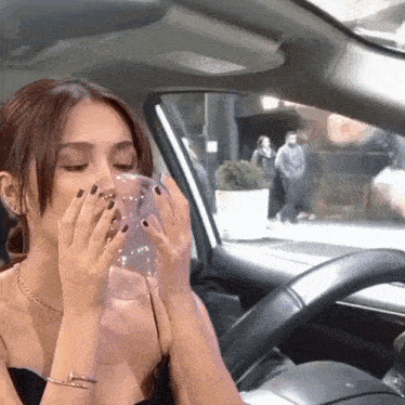 a woman in a car drinking from a clear cup