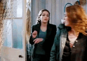 two women standing next to each other in a room with a door