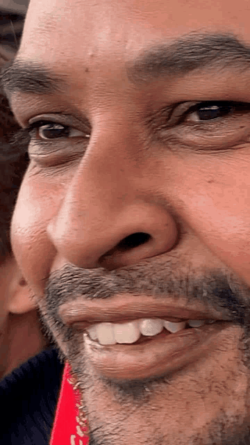 a close up of a man 's face with a red scarf around his neck that says coca cola on it