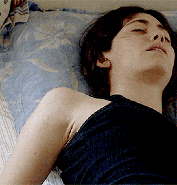 a woman with her eyes closed is laying on a bed