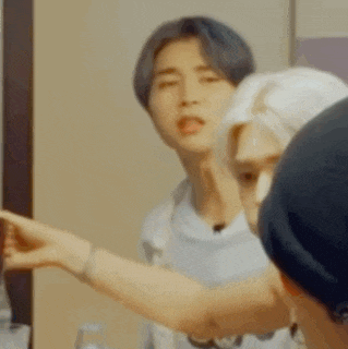 a group of people are standing in front of a mirror and one of them is pointing at something .