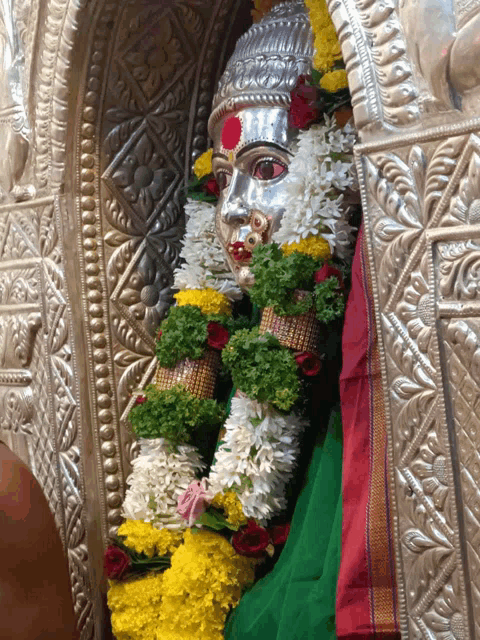 a statue of a woman with red eyes and flowers around her neck