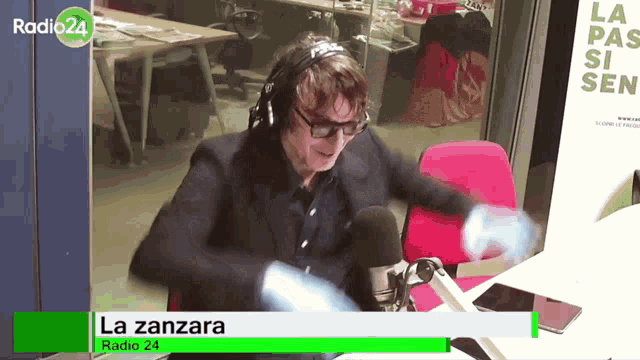 a man wearing headphones and glasses is dancing in front of a microphone for radio 24