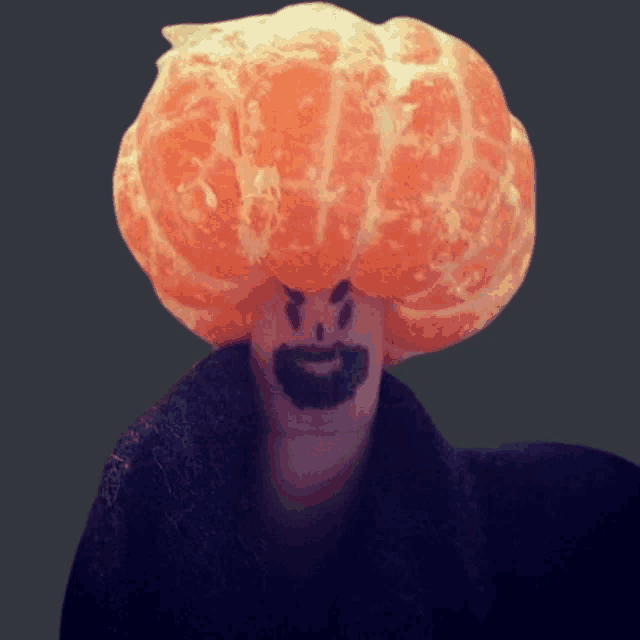a finger with a face drawn on it and a tangerine on it 's head