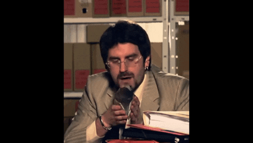 a man in a suit and tie holds a microphone