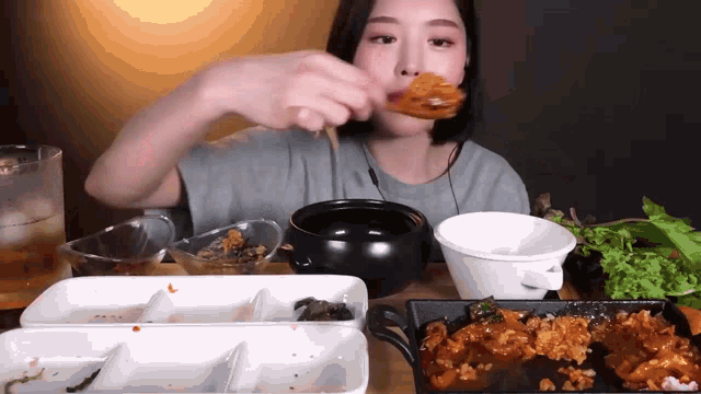 a woman is sitting at a table with plates of food and a bowl of soup
