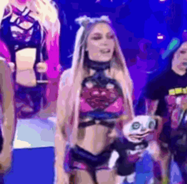 a woman in a pink top and shorts is holding a stuffed animal while standing on a stage .