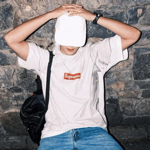 a man wearing a supreme t-shirt and a white hat