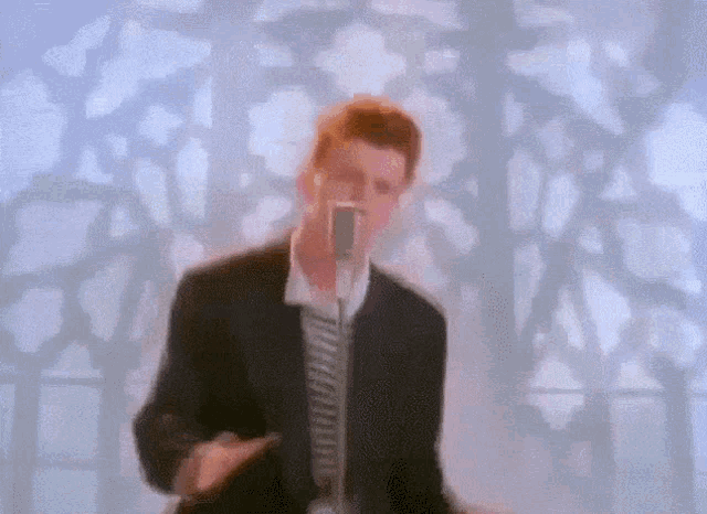 a man in a suit is singing into a microphone in front of a stained glass window