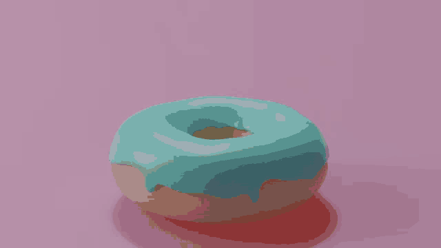 a donut with blue frosting is on a pink background