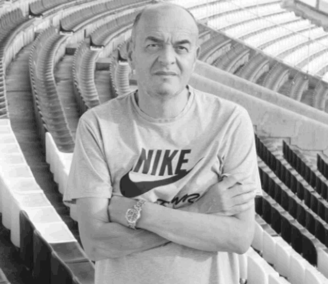 a man wearing a nike t-shirt stands in a stadium