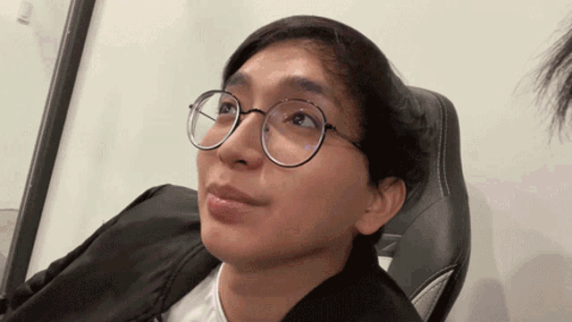 a man wearing glasses and a black jacket looks up