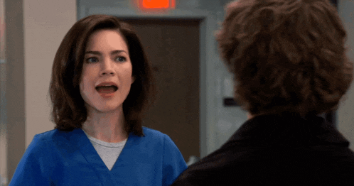a woman in a blue scrub talking to a man
