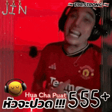 a man wearing headphones and a red manchester united shirt is laughing .