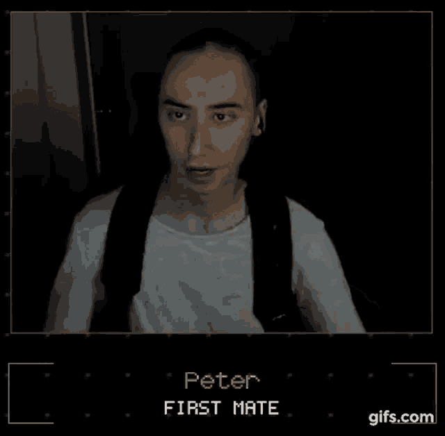 a man in a white shirt and black suspenders is sitting in a dark room and talking .