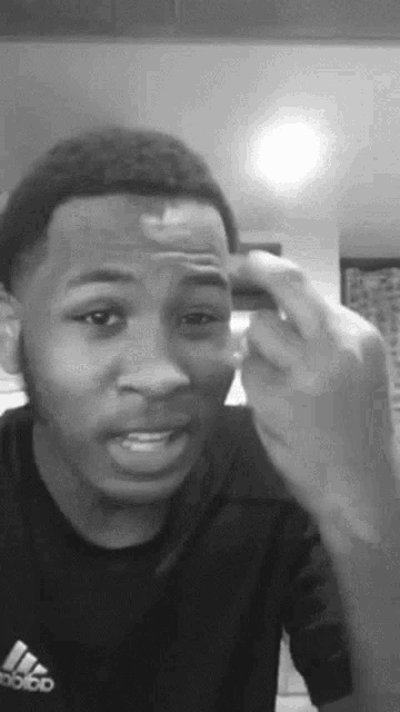 a black and white photo of a young man wearing an adidas shirt