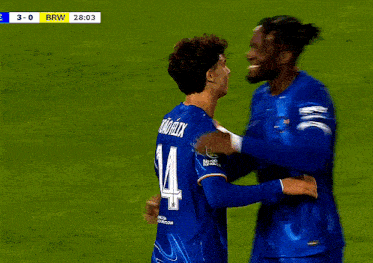 two soccer players are hugging each other and one has the number 14 on their jersey