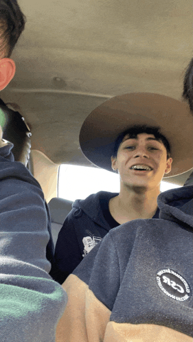 a man wearing a cowboy hat and a hoodie with the letter s on the back