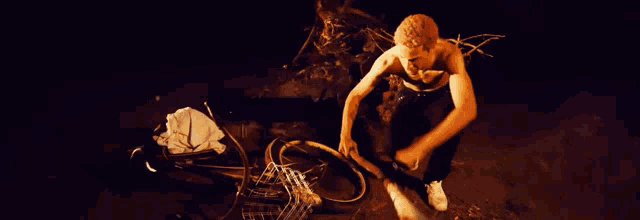 a shirtless man is working on a bicycle tire