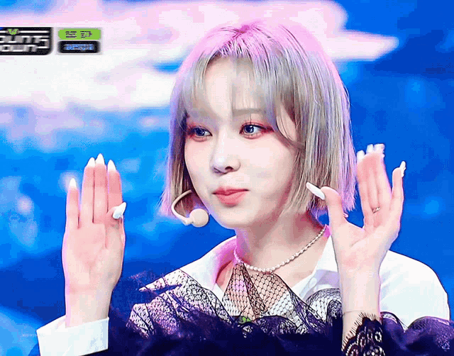 a woman with purple hair and white nails holds her hands up