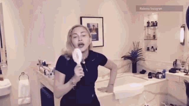 a woman in a black shirt is singing into a white microphone in a bathroom