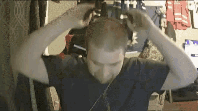 a man is wearing headphones and holding his head .