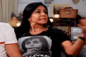 a woman is sitting on a couch wearing a black shirt with a picture of a woman on it .
