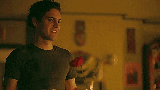 a man is smiling while holding a red rose .
