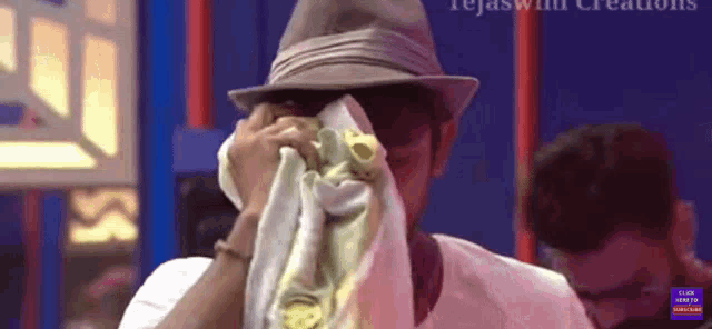 a man wearing a hat is covering his face with a towel and the words click here to view video below him