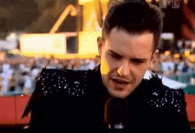 a man speaking into a microphone with a crowd behind him
