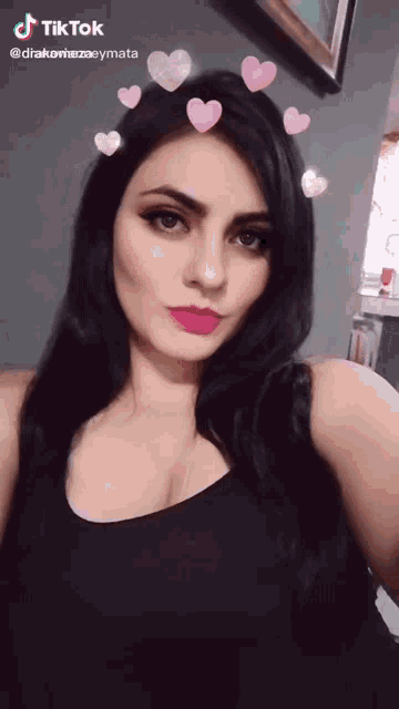 a woman wearing a black tank top has hearts on her hair and a tiktok watermark