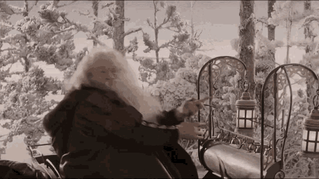 a man with a long beard is sitting on a bench in the snow