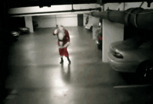 a man dressed as santa claus is walking in a garage